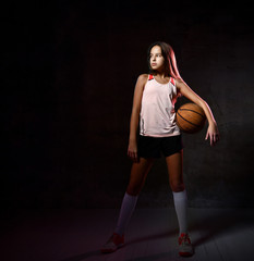 Fototapeta na wymiar Beautiful caucasian teen woman in sportswear playing basketball . Sport concept isolated on black background.