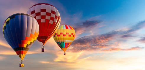 Heißluftballons der schönen Landschaft, die bei Sonnenuntergang über den Himmel fliegen
