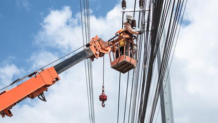 Two electrician workers are climbing on the electric poles to install and repair power lines.