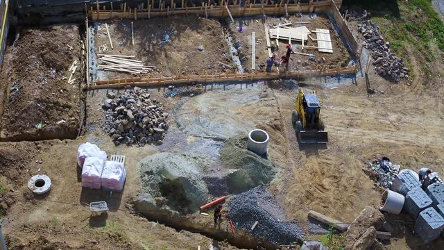 workers laying down the basement of a house with the help of skid steer loader