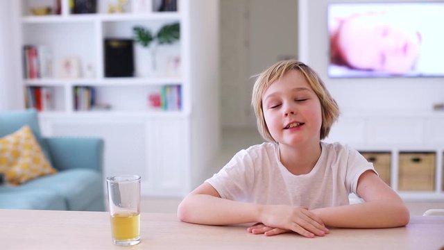 young boy, kid drinks juice at the table in living room