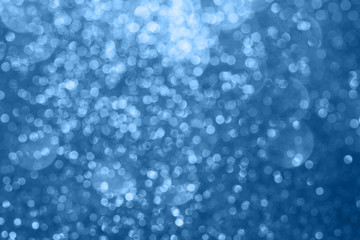 Abstract composition. Blurred photo of glitter with beautiful bokeh in classic blue, color of the year 2020. Defocused light.