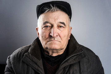Senior man portrait in studio 80 years old man caucasian with gray white hair wearing hat cap