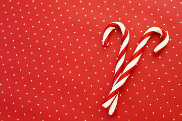 Two old fashioned candy canes on red background with gold dots, copy space, styled Christmas photo