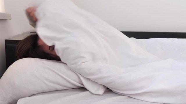 Lazy weekend wakeup, young adult woman does not want to get out of bed , white bedroom lit by morning sun. Girl idly pandiculate and don't want to leave soft place. 4k