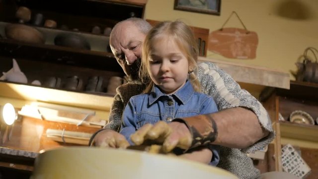 Pottery workshop. Grandpa teaches granddaughter pottery