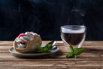 air cake on a saucer, steaming tea on a wooden background