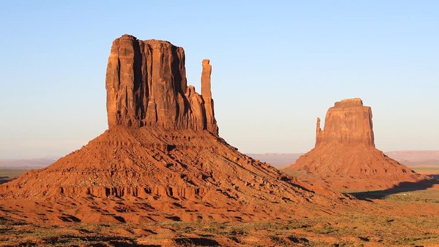 View of famous mesa butte formations closeup timelapse with red orange rock color on horizon in Monument Valley canyons during sunset in Arizona