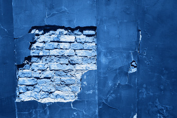 Cracked and textured blue wall, plaster background. Color of the year 2020 concept.
