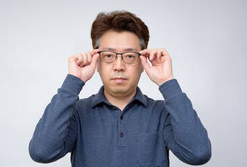 Asian middle-aged male trying to take off glasses and see something. poor sight, presbyopia, myopia.