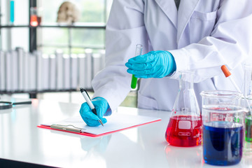 Scientists are recording results in glass bottles on a notebook.