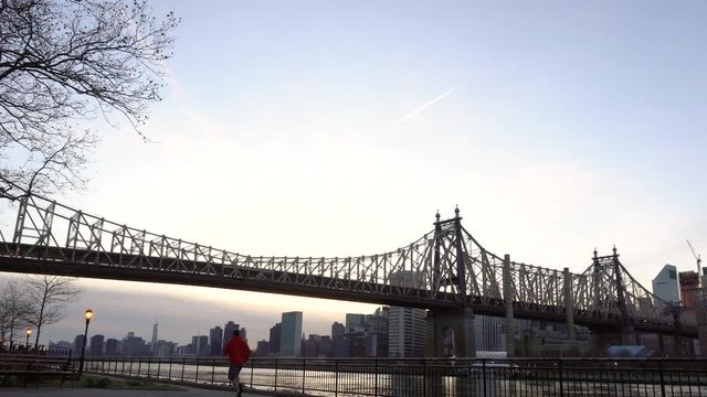 NEW YORK CITY, USA - NOVEMBER 30, 2019 : Man running in Queensbridge park with Ed Koch Queensboro Bridge view in the evening