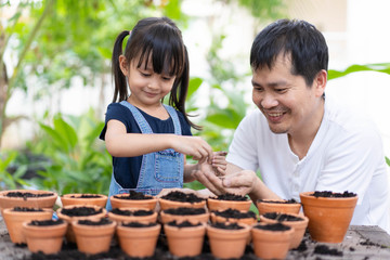 Asian father and daughter are enjoy helping together to seeding the plant, concept of parent...