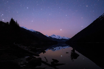 Night starry sky reflecting in calm lake in wilderness Canada