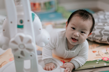 Asian baby boy lying on play mat with toys during tummy time at home