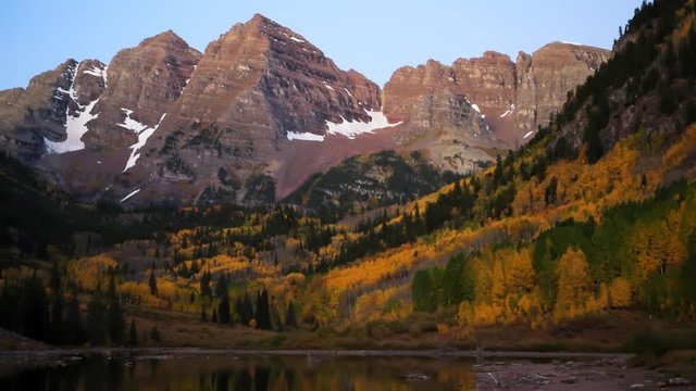 Maroon Bells morning sunrise timelapse with water reflection in Aspen, Colorado with rocky mountain and autumn yellow foliage on trees