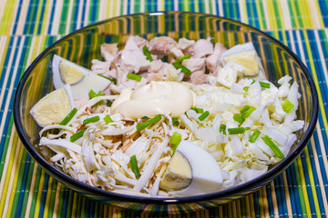 Dietary salad for proper nutrition with chicken and eggs on a green mat.