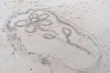 Flower drawn in the sand at a beach.