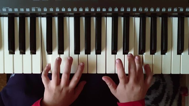 a child plays the piano .hands and keys close-up, top view