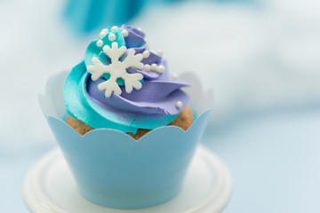Set of tasty cupcakes with blue and purple cream icing on a pink tray on blue background and defocused lights. Selective focus. Pastel colors. Party concept. Children's party decoration.
