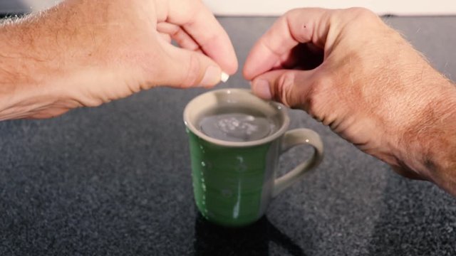 white powder pills in a capsule broken and poured into a cup