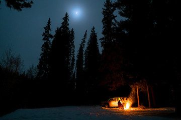 People camping under starry sky near campfire in winter in remote landscape in  Canada - 307537045