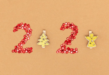 2020 made of red sparkles and decorative golden christmas trees on craft sheet of paper. Happy new year 2020 concept