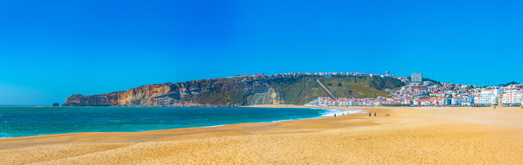 People are enjoying a sunny day on a beach in Nazare in Portugal