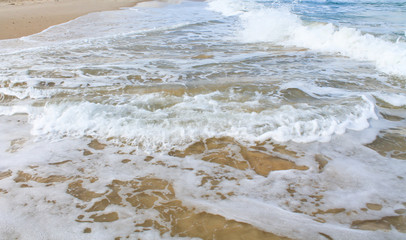 Sea foam on the sandy beach at Bat Yam, Israel. Waves on the blue stormy sea. Mediterranean coastline. Travelling picture. Turquoise water and sandy beach