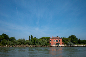 Fototapeta na wymiar Red house by water, island of Mazzorbo, near Burano, Venice, Italy