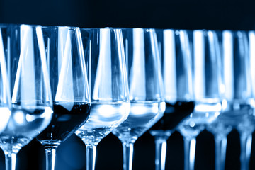Wine glasses in a row. Buffet table celebration of wine tasting. Nightlife, celebration and entertainment concept. Horizontal, toned blue
