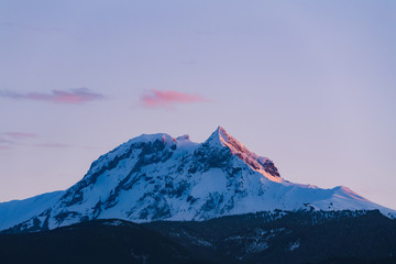 Mount Garibaldi covered in snow with last sun ray during red sunset in winter