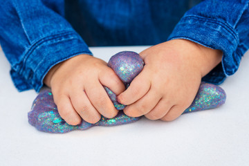 Blue magic glitter slime on a white background. Close up of hands.