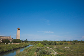 Fototapeta na wymiar Cathedral of Santa Maria Assunta and bell tower by river on island of Torcello, Venice, Italy