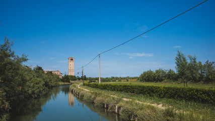 Cathedral of Santa Maria Assunta and bell tower by river on island of Torcello, Venice, Italy