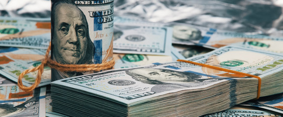 Cash hundred dollar bills, dollar background image. A stack and roll of one hundred American bills.