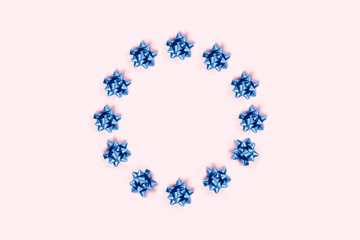 Christmas pink background with circle frame of blue bows.