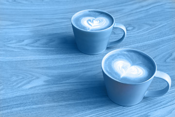 Cups of cappuccino with latte art in the wooden table. Trendy 2020 color concept.