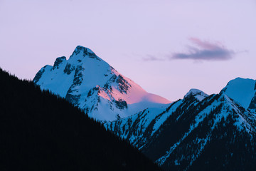 Pink and orange last light on snow covered mountains during sunset in winter in Canada - 307542096