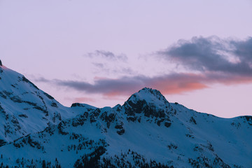 Pink and orange last light on snow covered mountains during sunset in winter in Canada - 307542249