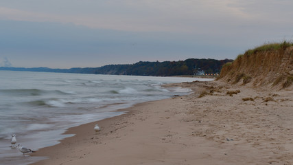 Photo of a sandy Lake Michigan beach and shoreline on a cloudy day with small waves and surf 