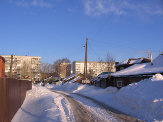 narrow passage between private houses in the village in winter covered with snowdrifts