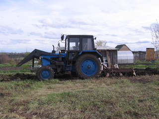 Fototapeta premium the tractor plows the land in the field rural labor in the spring digs up the garden