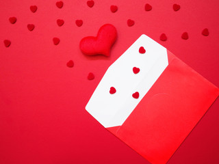 Opened envelope and red heart shape on red background.