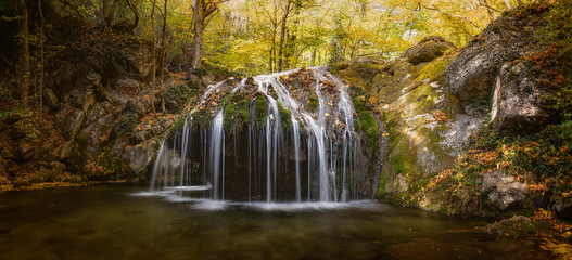 Beautiful waterfall in the autumn forest. October time. Scenic view