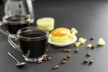 Black coffee in a coffee cup and with saucers Complete with coffee beans and bread on the black table