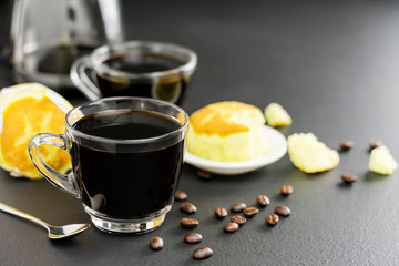 Black coffee in a coffee cup and with saucers Complete with coffee beans and bread on the black table