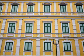  Row of blue windows on a yellow wall.
