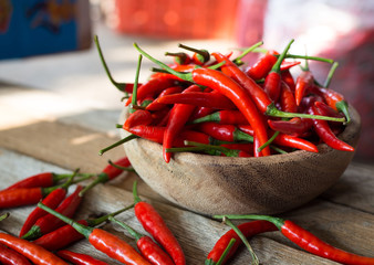 Fresh red chili peppers in wood bowl on wood table background