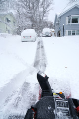 snow blower removing snow on driveway after snow storm